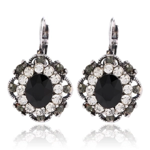 Macro detail of retro alloy earrings featuring oval black resin gems and crystal accents