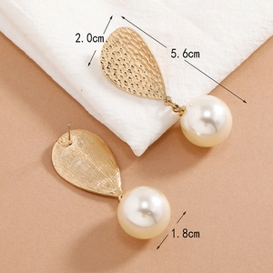 Detailed size view of gold teardrop earrings with textured metal and large white pearls