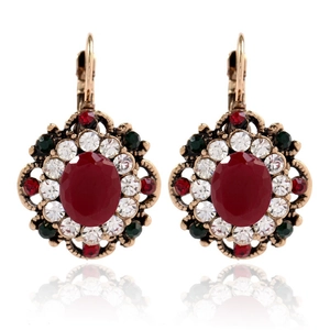 Detail of vintage gold earrings with red oval gemstone and multi-color crystals