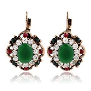 Detailed macro view of vintage gold-plated earrings with green gems and colorful rhinestones
