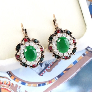 Macro detail of vintage bohemian earrings with green oval stone and crystal petals