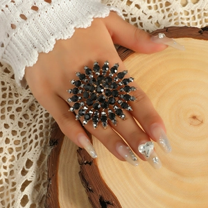 Detailaufnahme des großen schwarzen Sonnenblumenrings mit Kristallen an der Hand