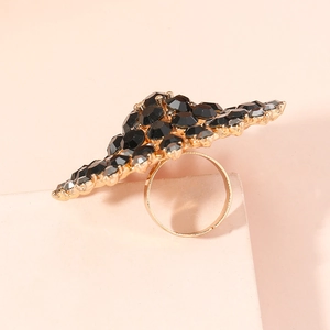 Makro-Detail des Statement-Rings mit schwarzen Edelsteinen und goldener Welle