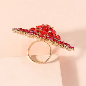 Nahaufnahme eines luxuriösen Goldrings mit tiefroten Kristallen im Sonnendesign
