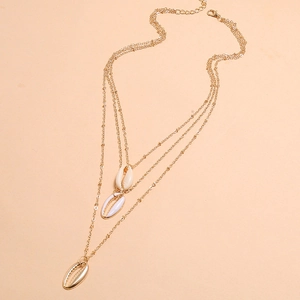 Dettaglio di una collana a tre strati placcata in oro con ciondoli a forma di conchiglia