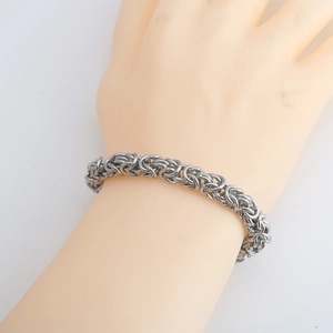 Handcrafted silver stainless steel Byzantine chain bracelet worn on a wrist over white background