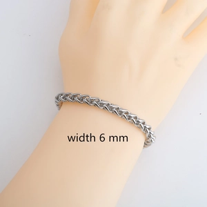 Detalle de una pulsera de cadena de trigo de acero inoxidable plateado de 6 mm en la muñeca