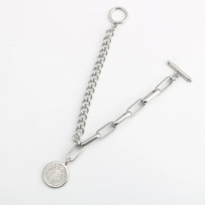 Detalle de pulsera de cadena mixta plateada con medalla San Benito y cierre de OT