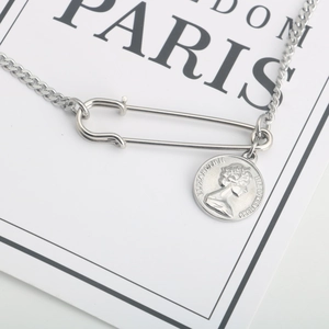 Macro view of retro titanium steel chain necklace with safety pin and coin pendant detail