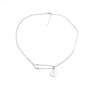 Detailed close-up of a silver pin and Elizabeth II coin pendant on a curb chain