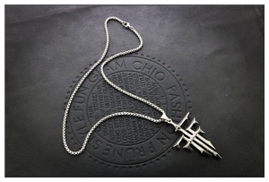 Detailweergave van de zilveren geometrische kruishanger aan een stalen kralenketting