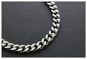Macro detail of high-polished silver cuban chain link necklace on black leather background