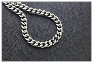 Macro shot of polished silver stainless steel curb chain links on black leather texture