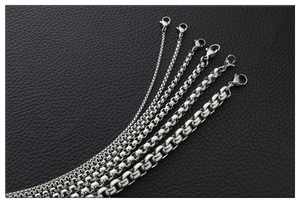 Various thicknesses of stainless steel box chains with lobster clasps on black leather