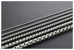 Macro view of five different sizes of polished silver steel box chains on black leather