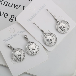 Macro detail of vintage coin earrings with queen head engraving on stainless steel