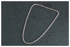 Detalle de collar de cadena box de acero inoxidable plateado sobre piedra gris