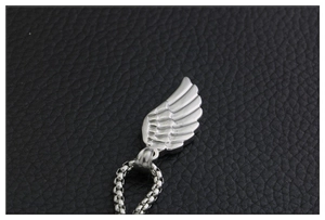 Vue macro détaillée du pendentif aile d'ange avec plumes texturées sur une chaîne en cuir noir