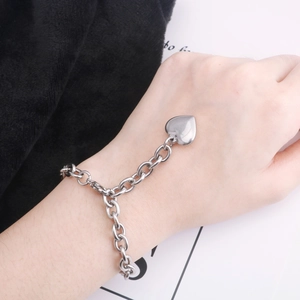 Gros plan d'un bracelet en acier titane argenté avec un grand pendentif en forme de cœur