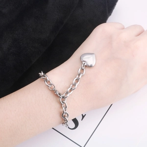 Gros plan d'un bracelet chaîne avec pendentif cœur argenté sur fond minimaliste chic