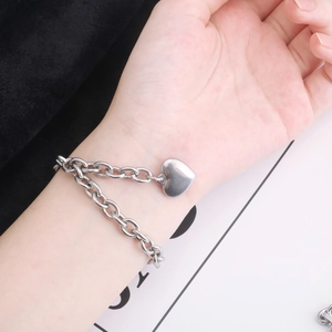 Vue détaillée du bracelet chaîne en acier inoxydable argenté avec pendentif cœur au poignet