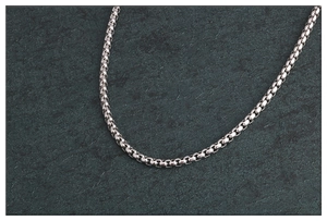 Collar de cadena box de acero inoxidable plateado sobre fondo de piedra gris oscuro