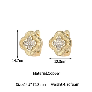 Detail of clover-shaped gold earrings with zircon pavé and brushed texture on copper base