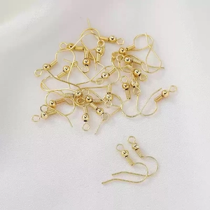 Close-up of DIY gold plated ear hooks with ball and coil details on white fabric