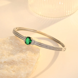 Detailed view of silver bracelet with emerald green zircon and pavé set white diamonds