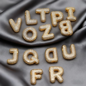 Colgante de letra de globo con circonitas micro-pave sobre fondo de seda oscura