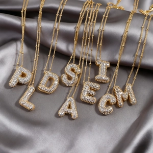 Collar con colgante de letras burbuja chapado en oro y circonitas sobre seda gris