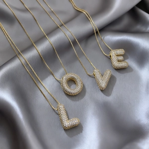 Detalle de los colgantes LOVE bañados en oro con micro-pavé de circonitas sobre seda