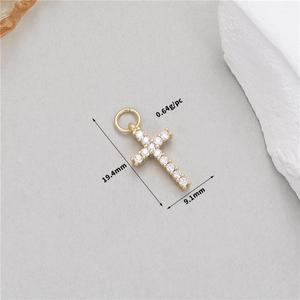 Detalle de un colgante de cruz dorada con circón blanco y medidas de 19,4x9,1mm