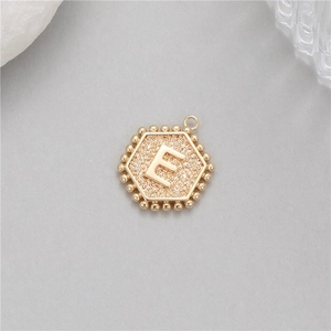 Detailed macro view of 14K gold plated hexagonal pendant with letter E and beaded edge