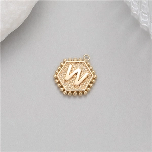 Detail shot of a 14K gold plated hexagonal pendant with embossed letter W and beaded edge
