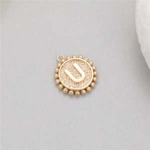 Detailed macro of 14K gold-plated initial U pendant with textured finish and beaded edge