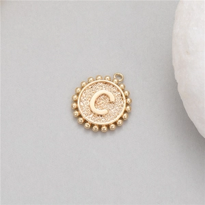 Detailed close-up of a 14K gold-plated circular pendant with a raised letter C and bead trim