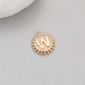 Detail of a 14K gold-plated round coin pendant with letter W and beaded edge