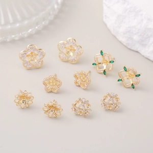 Macro detail of gold-plated cubic zirconia earrings showing intricate flower and geometric motifs