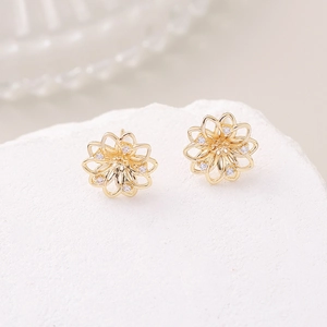 Exquisite hollow gold clover earrings with micro-inlaid zircons on a white stone pedestal