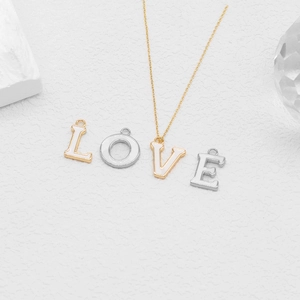 Detail of LOVE initial letter pendants with white enamel on textured stone