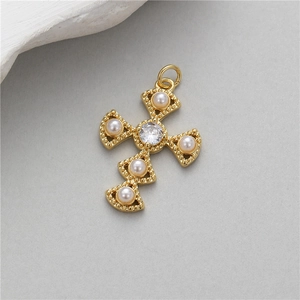 Golden cross pendant featuring five pearls and a central zircon on a textured background