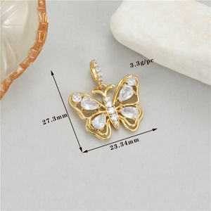 Macro shot of gold bow pendant with cubic zirconia wings showing size 27x23mm