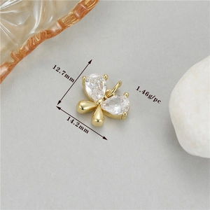 Macro view of gold bow pendant with pear-shaped cubic zirconia stones and measurements