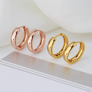Macro shot of polished rose gold and gold hoop earrings on a soft fabric background