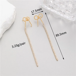 Detailed view of long tassel bow earrings with pearls, zircons and gold weave