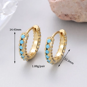Macro detail of gold hoop earrings with turquoise stones and clear zircon accents