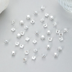 Macro view of silver square claw settings for DIY jewelry making on a grey background