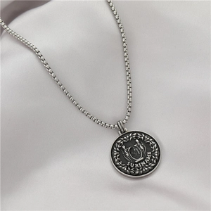 Detalle del relieve del escudo de Surinam en colgante de moneda plateada con cadena box