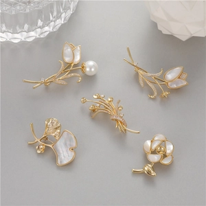 Broches élégantes tulipe et rose dorées avec nacre et zircons sur fond gris neutre